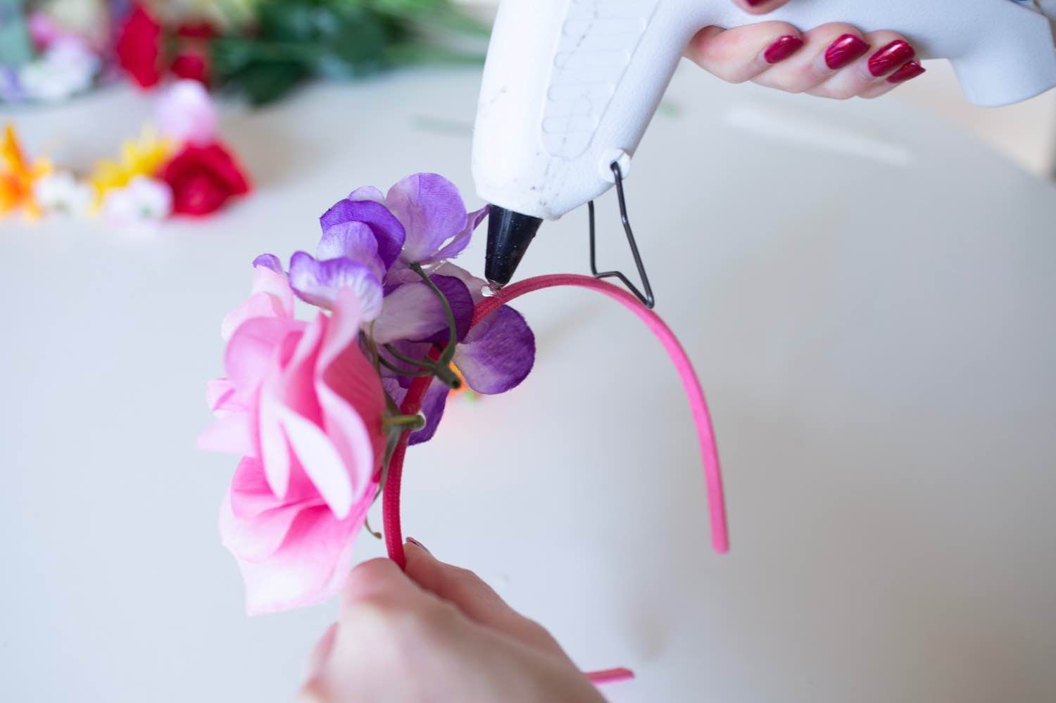 add more faux flowers to the headband with hot glue - diy flower crown pop shop america