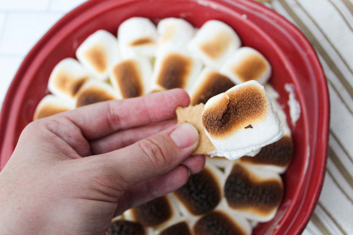 closeup hand holding s'mores dip on graham