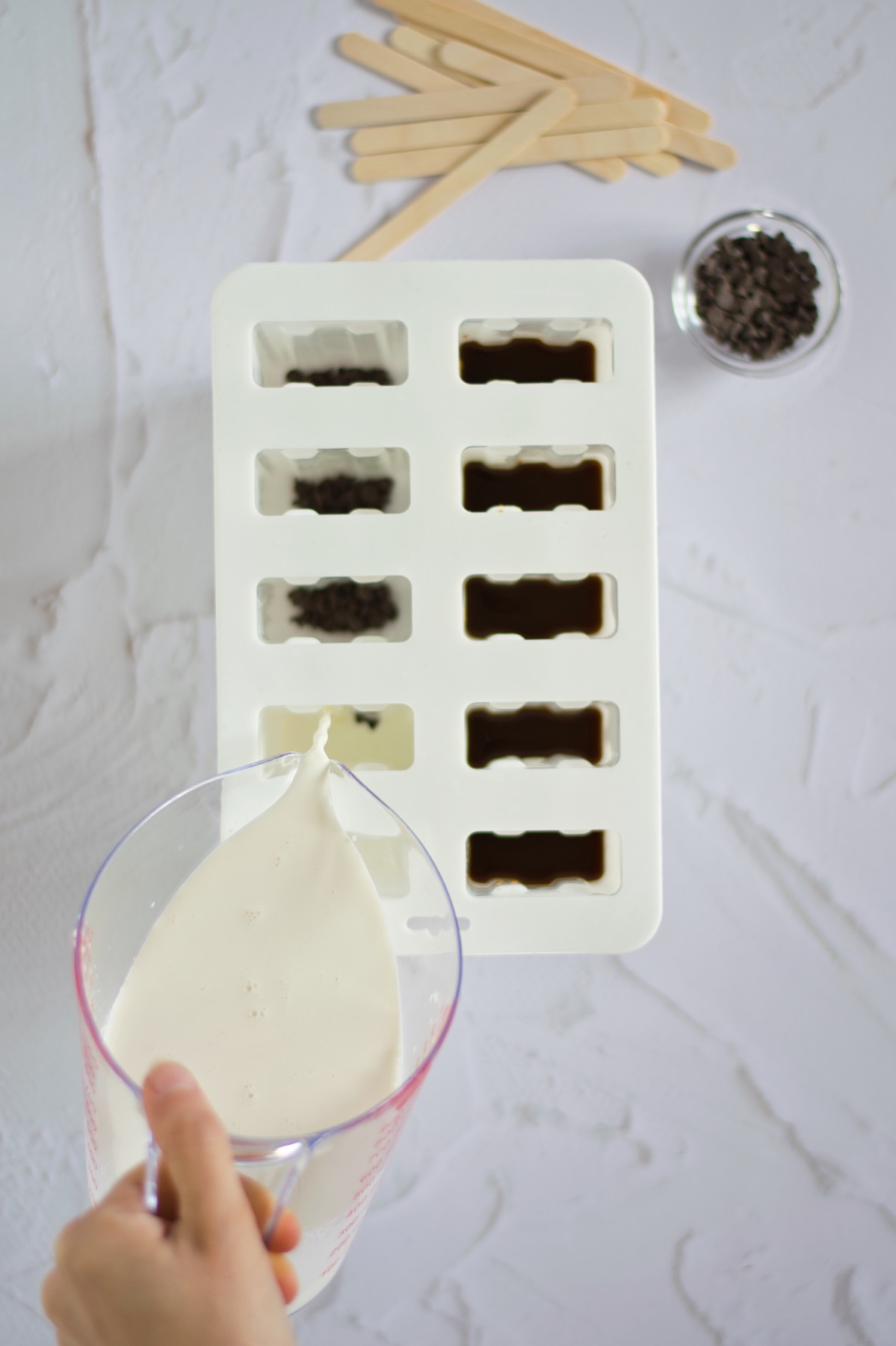 pouring cream into the popsicles molds for coffee pops