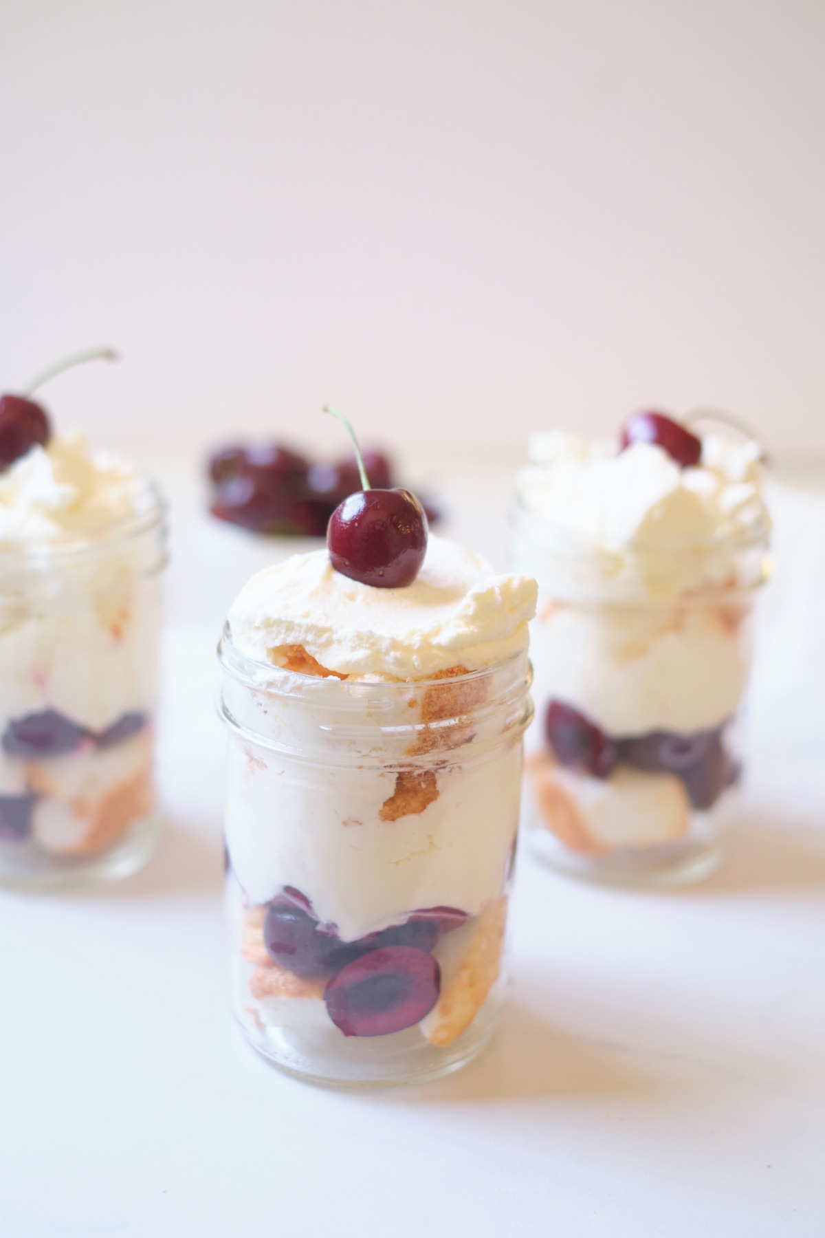 add cherries whipped cream to the mason jar parfaits